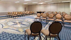 A conference room with rows of chairs, a patterned carpet, and a large meeting table. - Red Roof Inn & Conference Center McKinney (McKinney)
