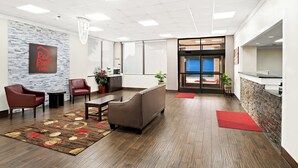 A modern lobby with a reception desk, seating area, and a view to the outside.