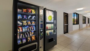 A vending machine with snacks and a drink dispenser in a hallway. - Red Roof Inn & Conference Center McKinney (McKinney)