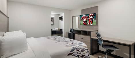 A hotel room with a bed, a desk, a chair, a TV, and a mirror.