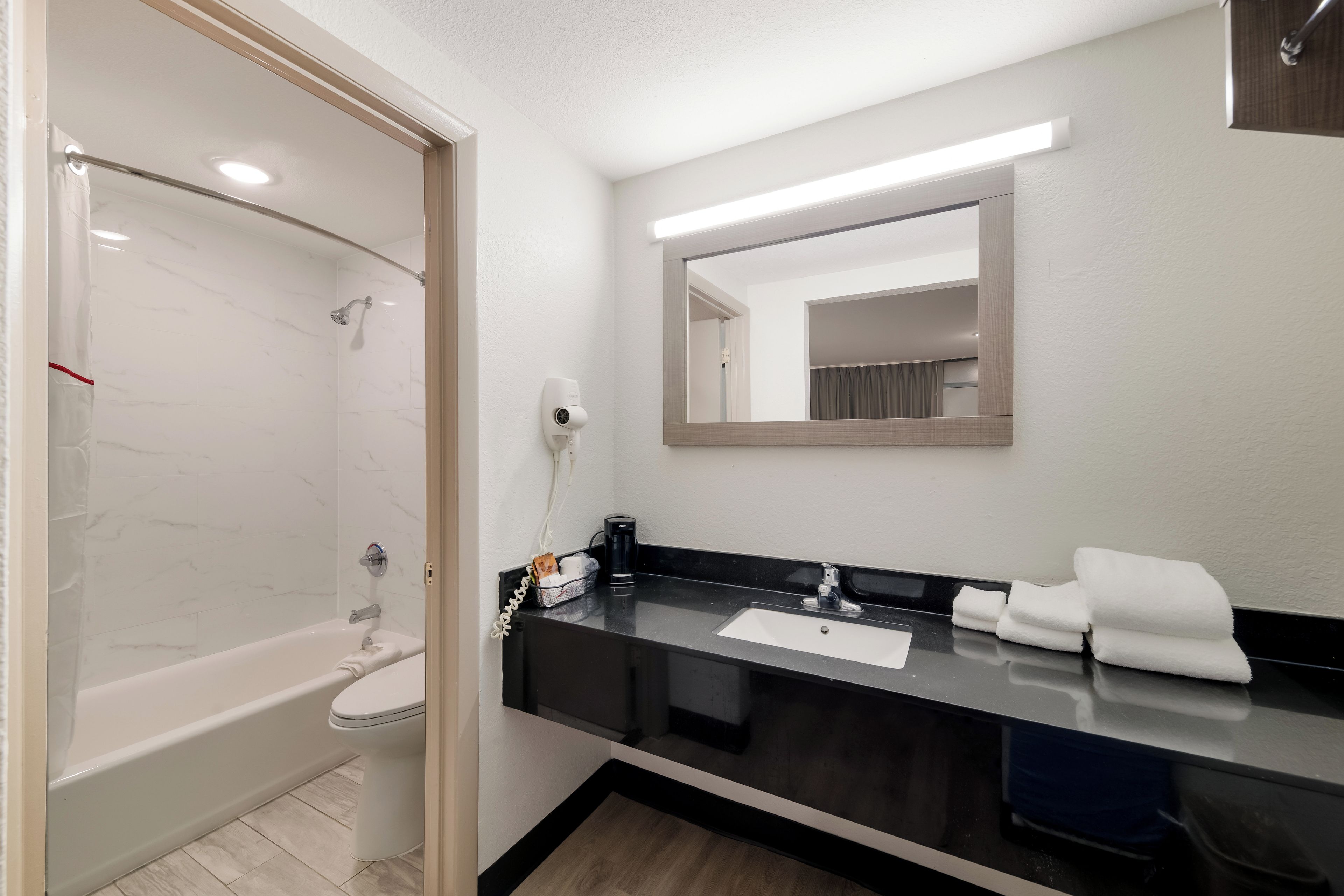 Un baño moderno con bañera, lavamanos y espejo.