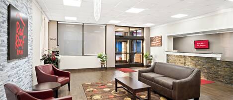 A lobby with a reception desk, seating area, and a wall-mounted TV.