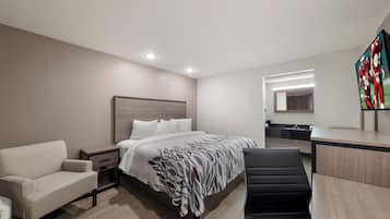 Una habitación de hotel con una cama, un escritorio, una silla, un sofá y un televisor.