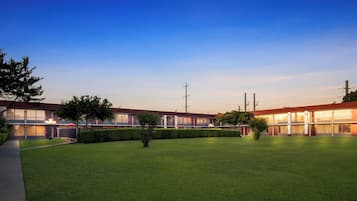 A hotel with a spacious lawn and multiple rooms with large windows.