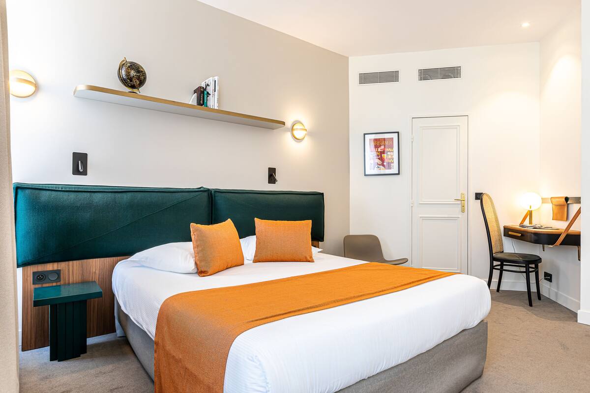 A neatly arranged hotel room with a large bed, a desk, and a chair.