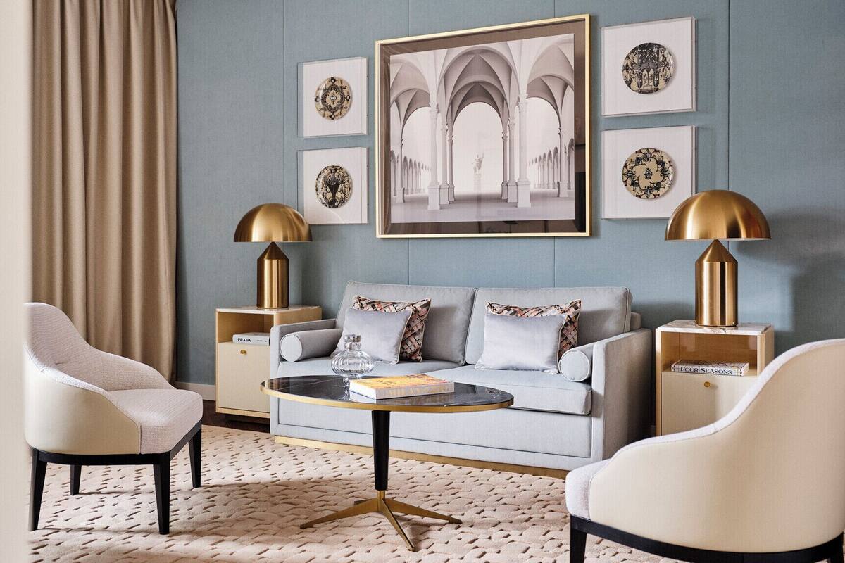 A modern living room with a grey sofa, two armchairs, a coffee table, and decorative lamps.