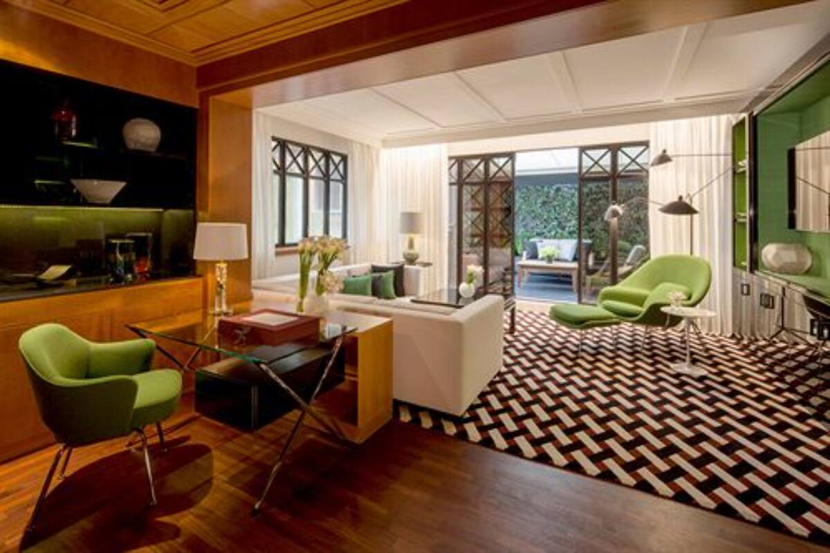 A modern living room with a geometric patterned floor, a green armchair, a white sofa, and a glass coffee table.
