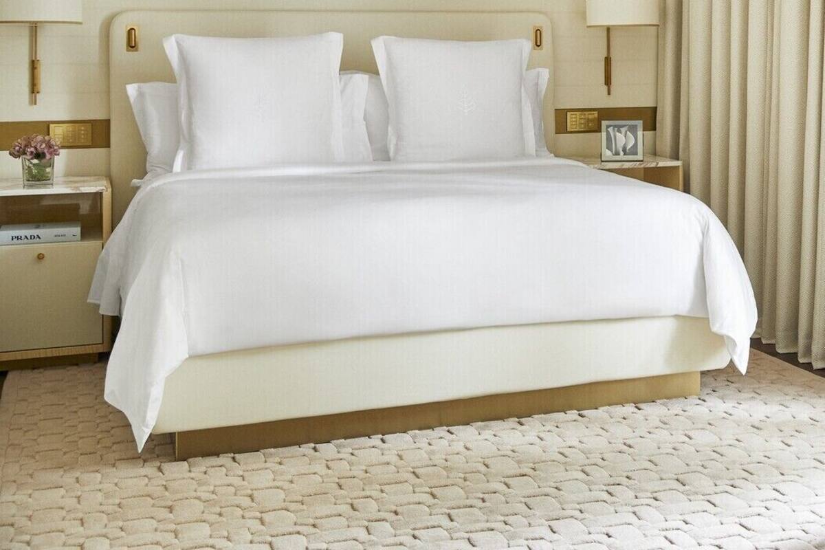 A hotel room with a large bed, two bedside tables, and a nightstand with a lamp.