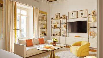 Een moderne woonkamer met een bank, een gele fauteuil, een salontafel en een televisie.