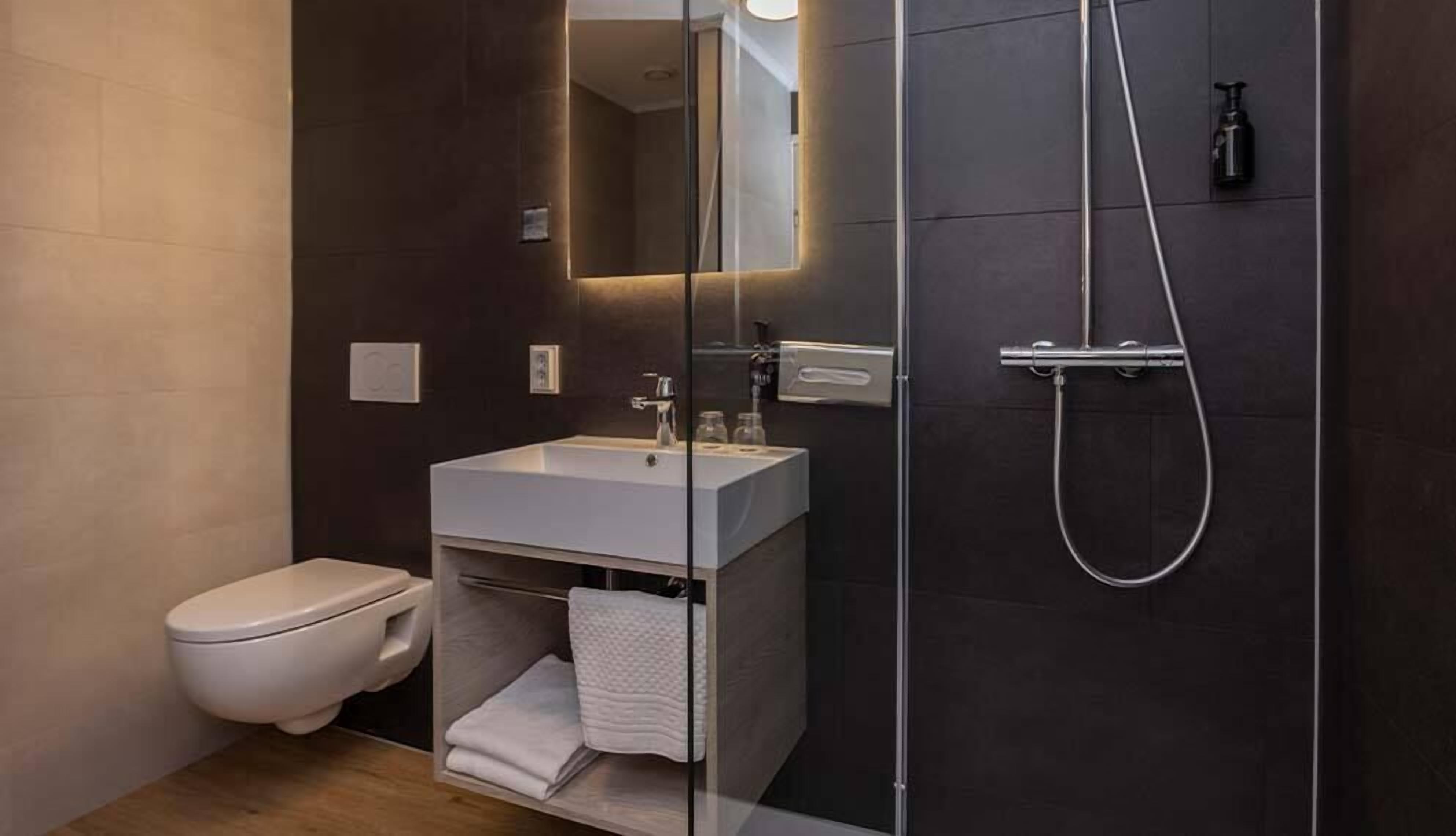 A modern bathroom with a toilet, a sink, and a shower.