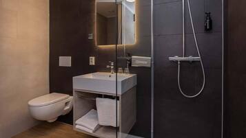 A modern bathroom with a toilet, a sink, and a shower.