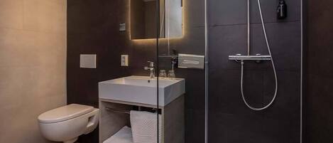 A modern bathroom with a toilet, a sink, and a shower.