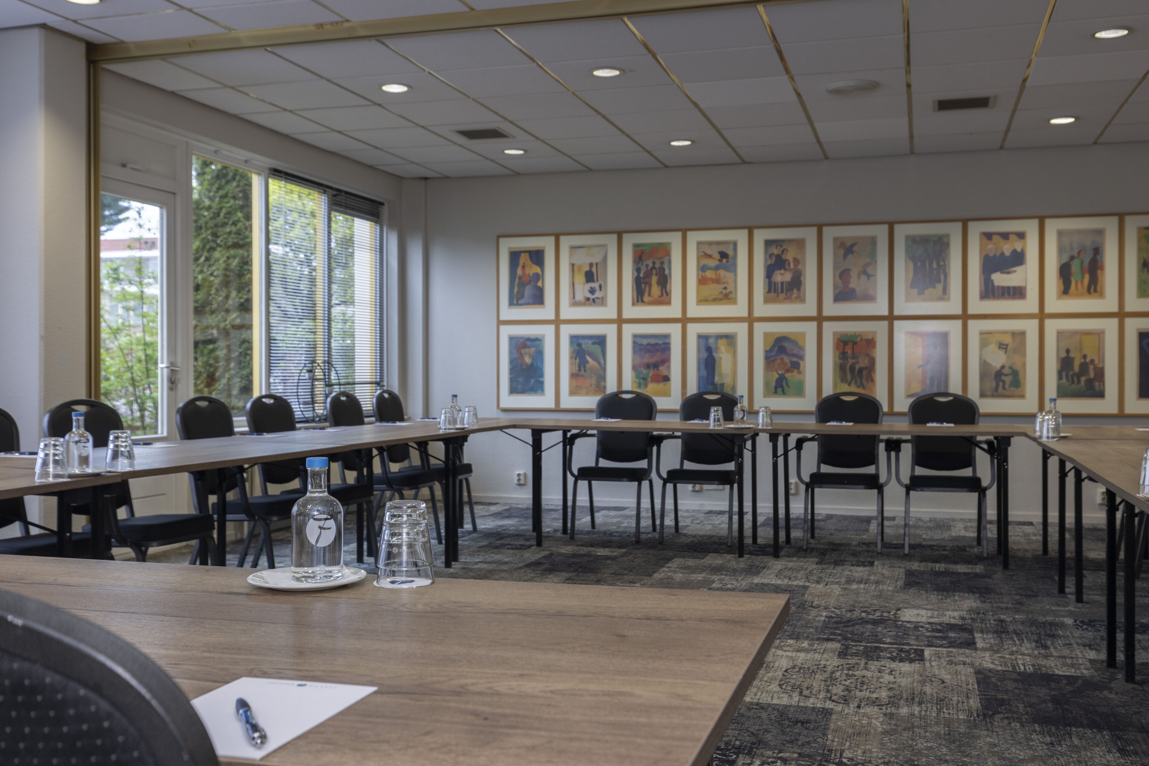 A conference room with a long table, chairs, and framed artwork on the walls.