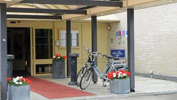 La entrada del Hotel Langewold, con un acceso cubierto, una alfombra roja y bicicletas estacionadas fuera.