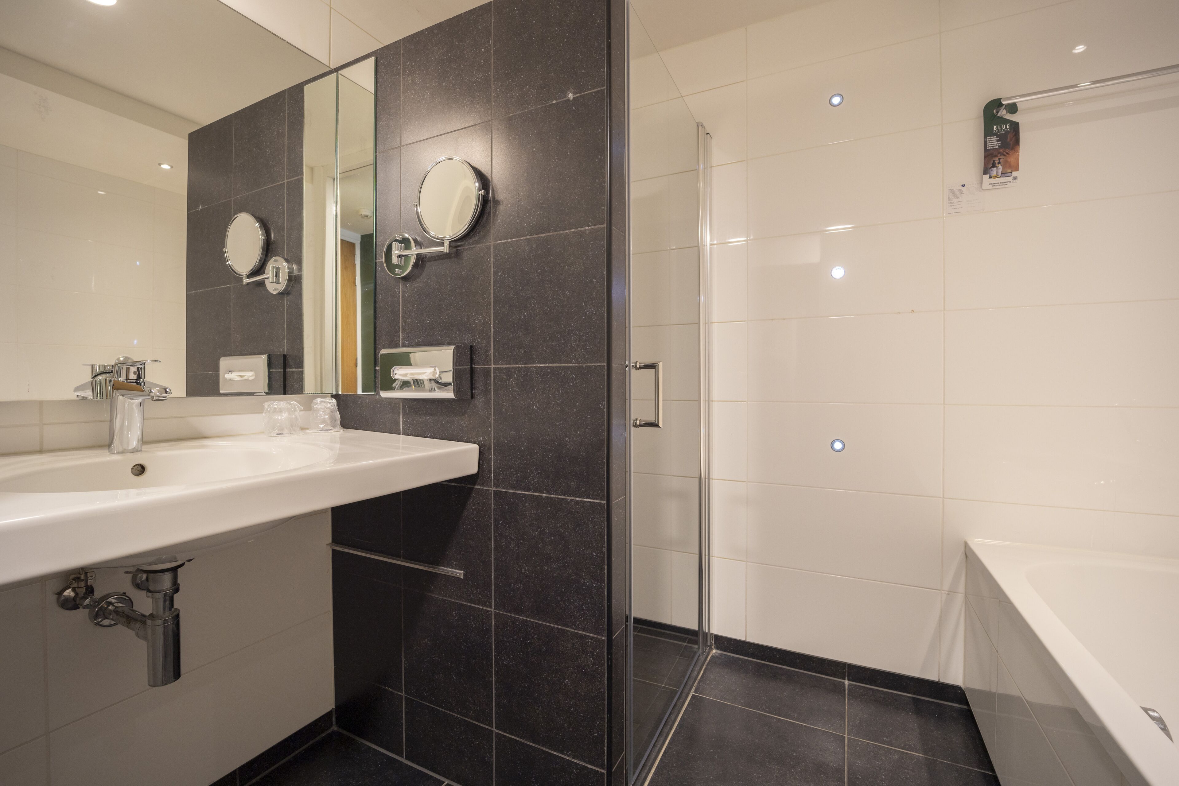 Ein modernes Badezimmer mit einem großen Waschbecken, zwei Spiegeln, einer Dusche und einer Badewanne.