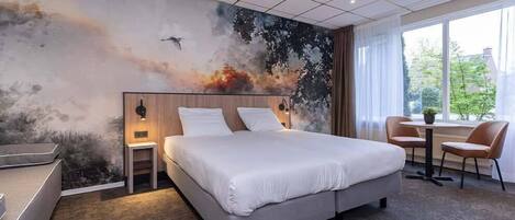 A modern hotel room with a large bed, a desk, and a chair.