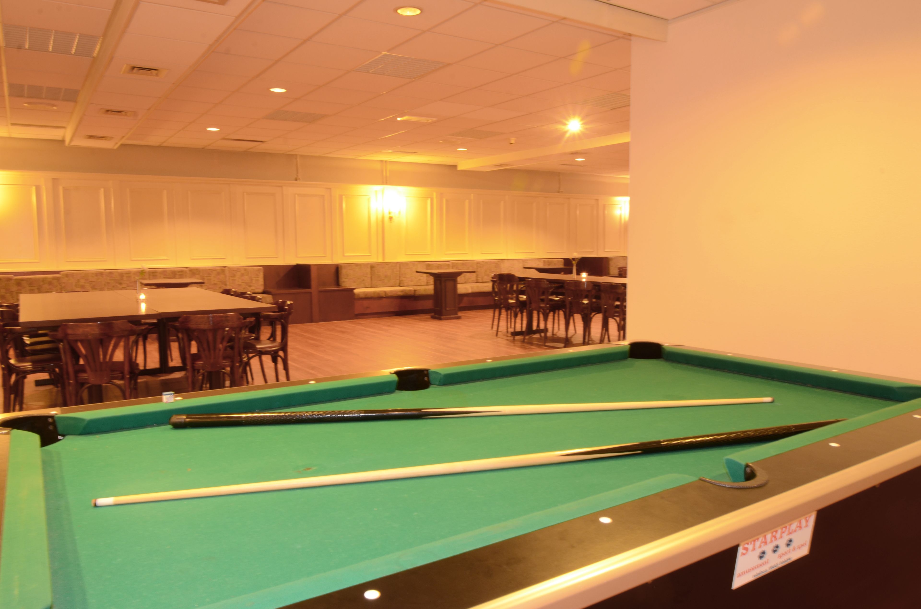 Una mesa de billar en una sala con zona de comedor y bar.