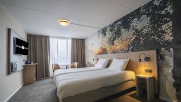A hotel room with a large bed, a TV mounted on the wall, a small table, and a chair.