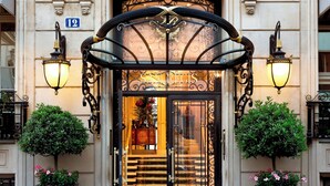 A grand entrance with a black metal archway, a glass door with a golden emblem, and two black lantern-style lights on either side. - Hôtel San Régis (Paris)