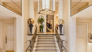 A grand staircase with ornate railings, a chandelier, and decorative sculptures. - Hôtel San Régis (Paris)