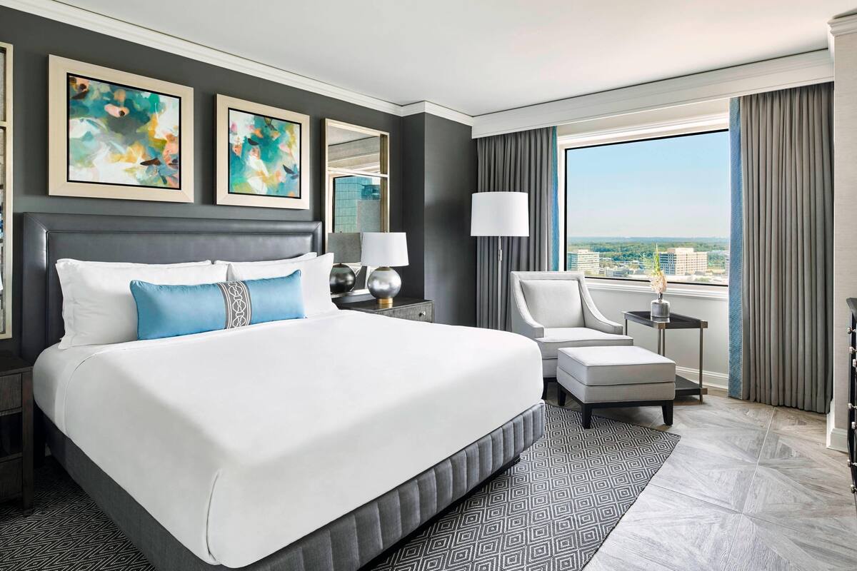 Une chambre d’hôtel moderne dotée d’un grand lit, d’un coin salon et offrant une vue sur la ville.