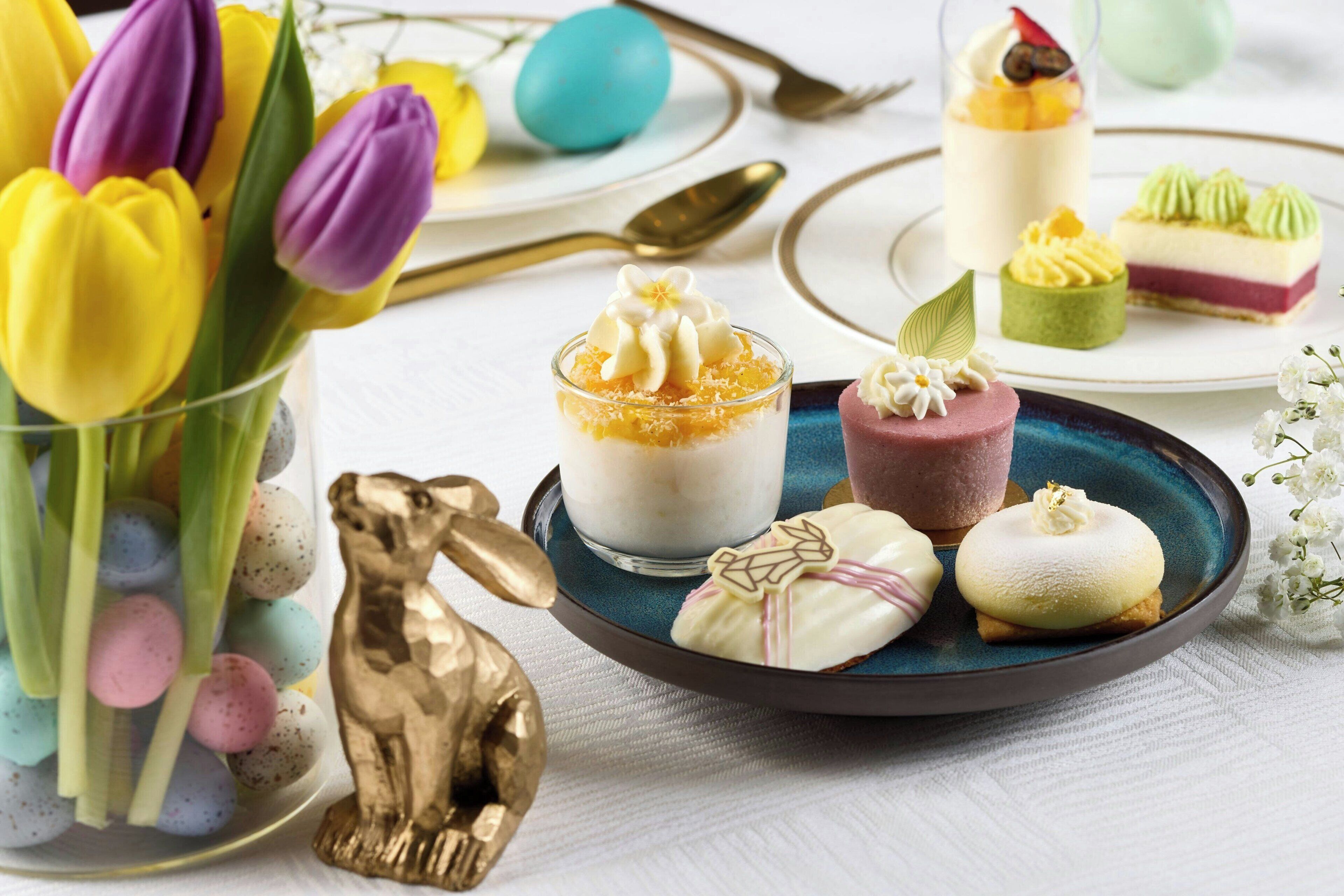 A table with various desserts and a golden bunny figurine.