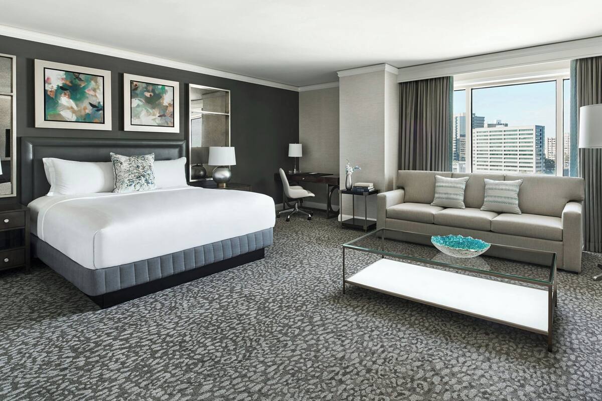Une chambre d’hôtel avec un grand lit, un canapé, un bureau et une vue sur la ville.