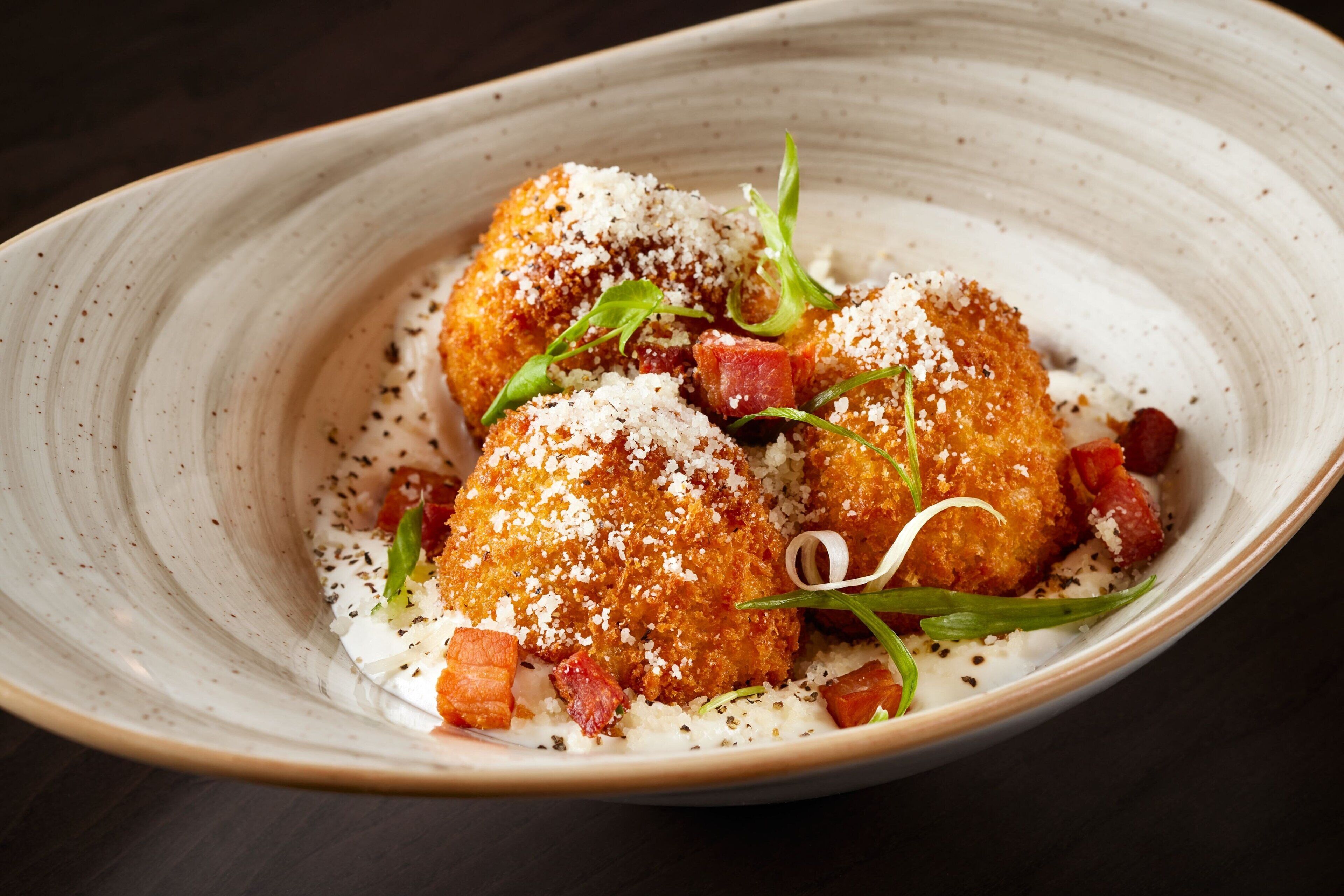 A dish with breaded chicken, garnished with herbs and cheese, served on a plate.