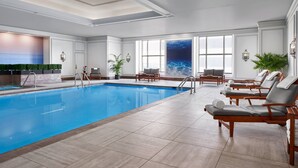 A swimming pool with lounge chairs and a mural of the ocean.