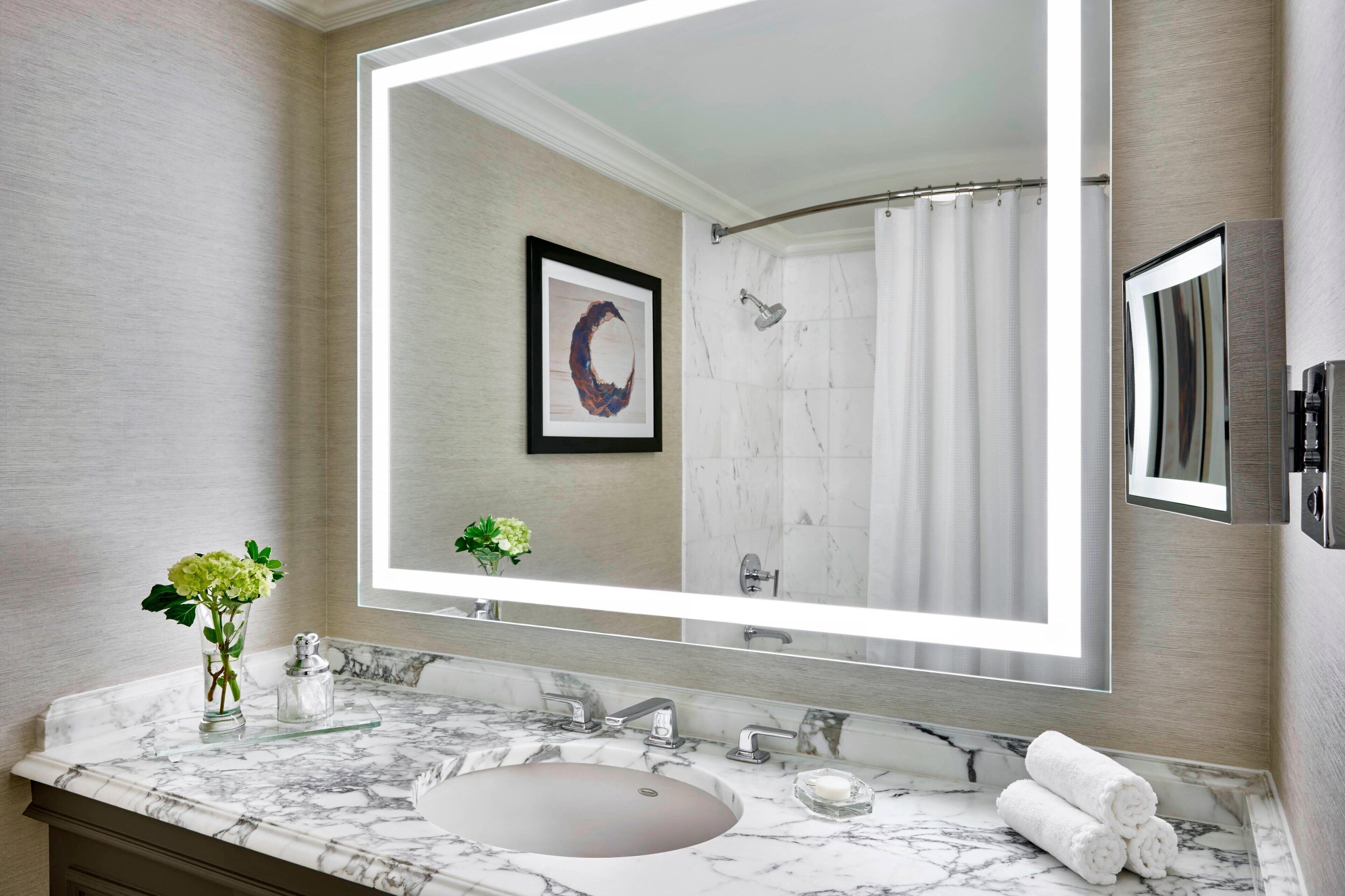 A bathroom with a large mirror, marble countertop, sink, and a shower curtain.