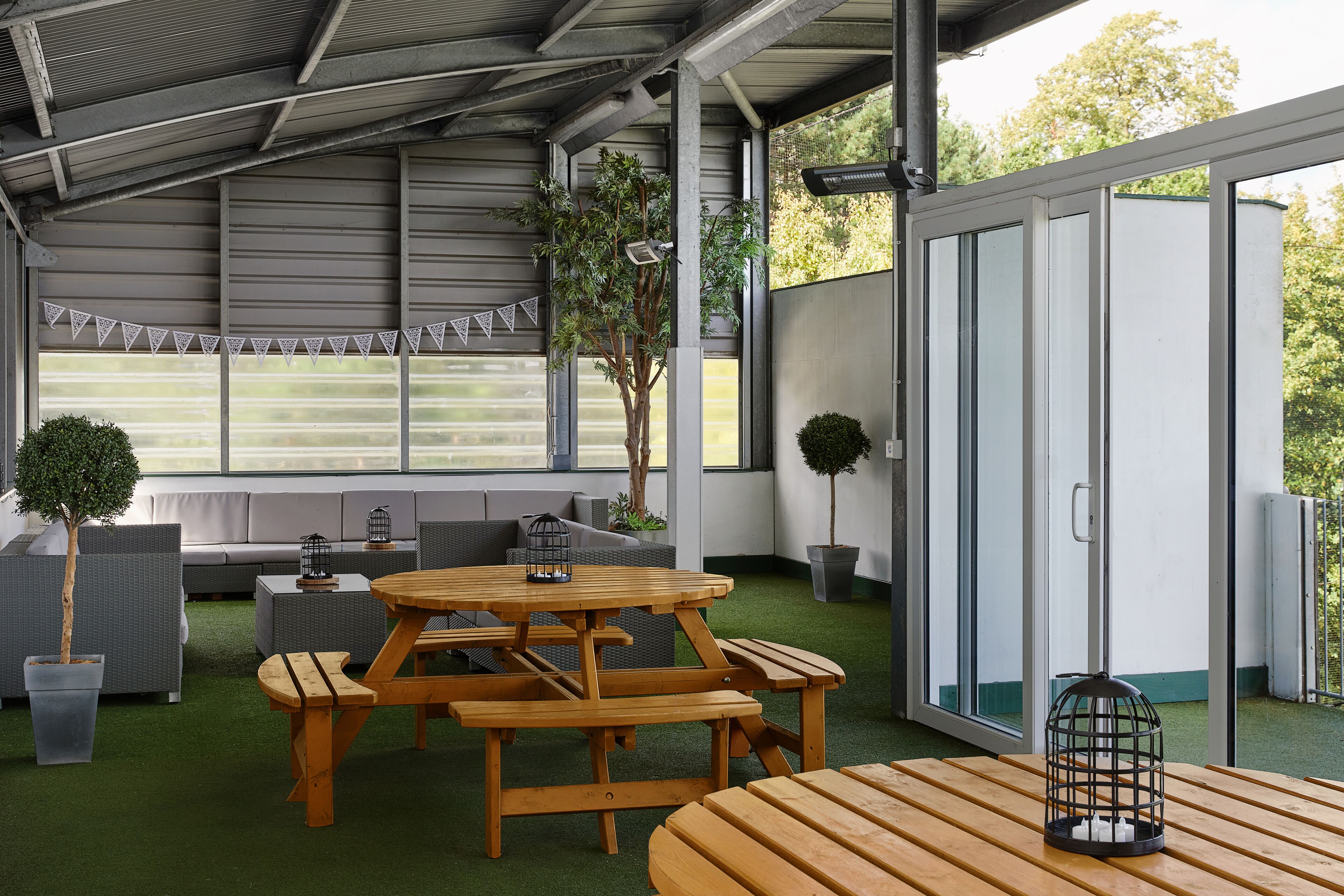 Un patio abrité avec une table de pique-nique en bois, des sièges et des plantes en pot.