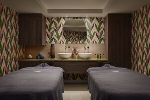 Quarto de hotel com um espelho grande, duas camas, uma pia e um porta-toalhas.
