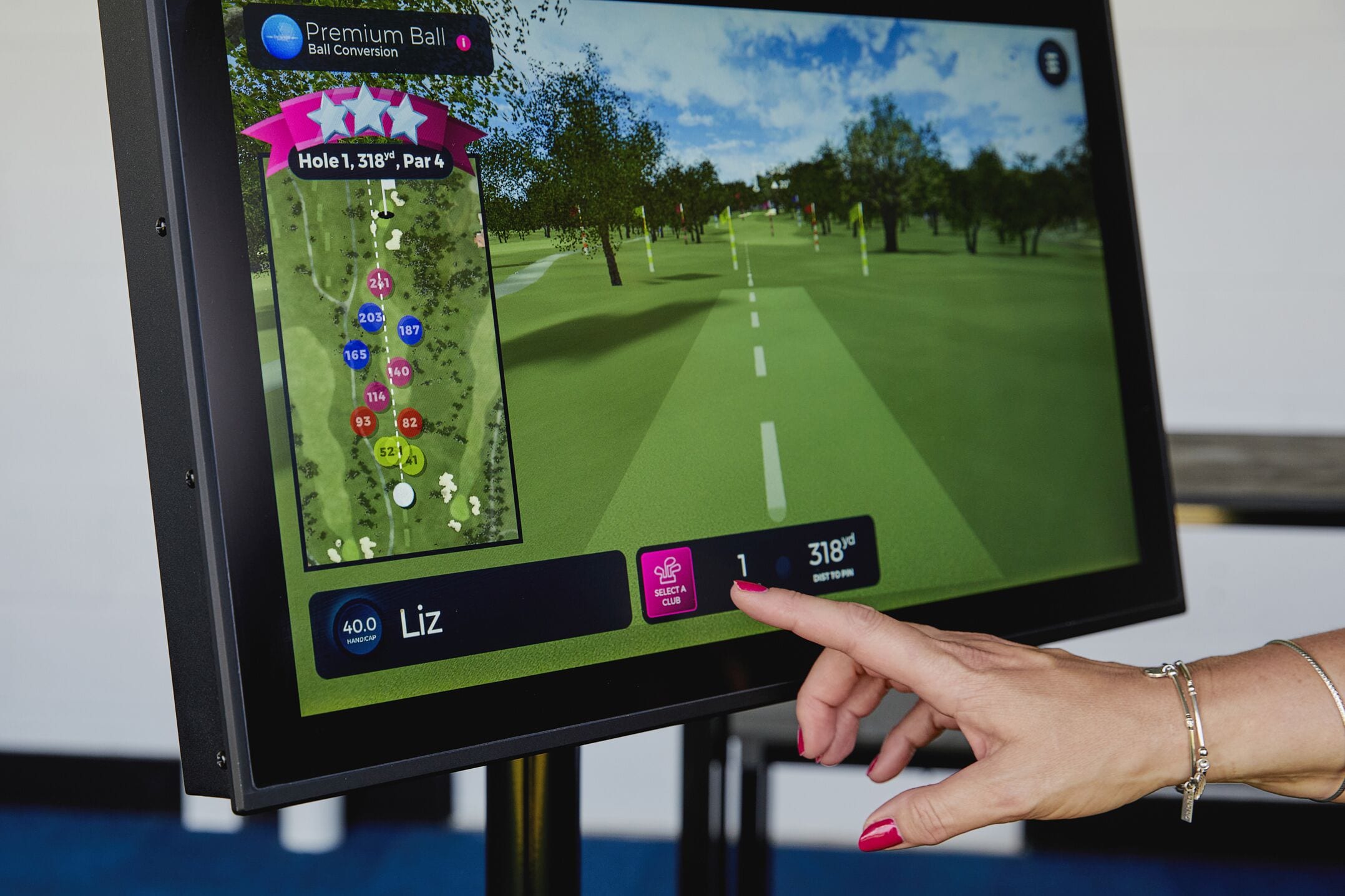Interfaz de un juego de golf digital que muestra un mapa de campo, tarjeta de puntuación y una mano señalando la pantalla.