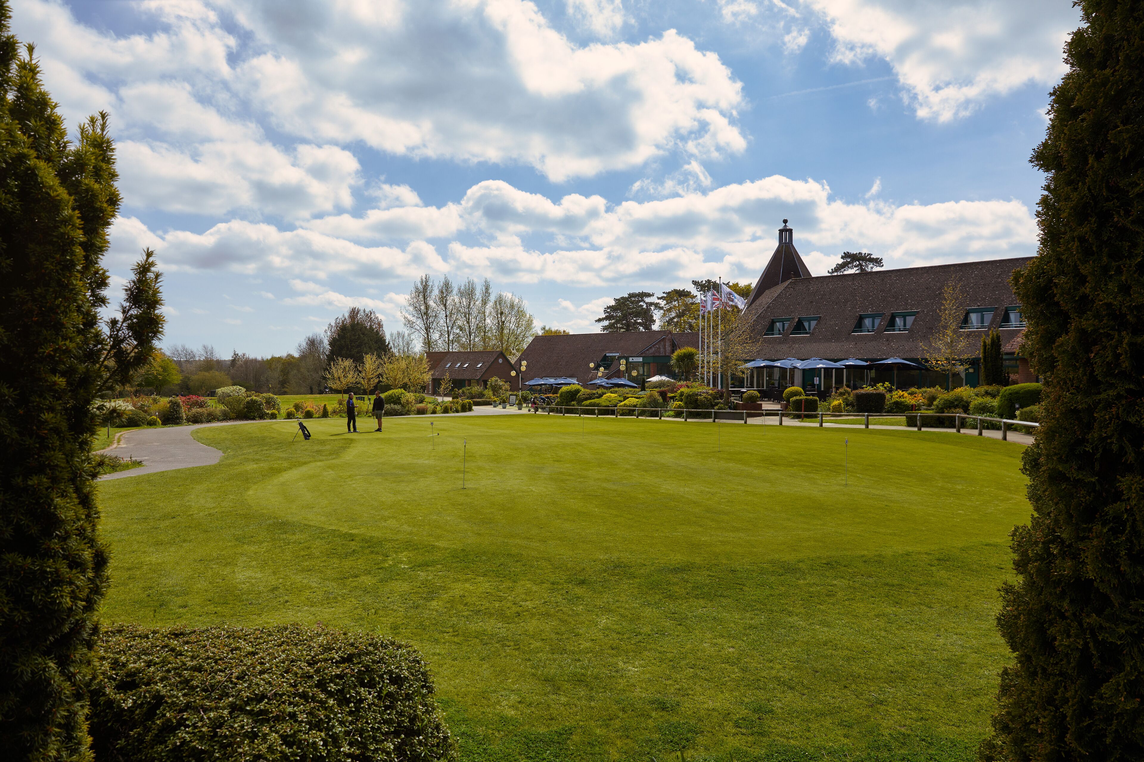 Un parcours de golf doté d’un club-house et d’un grand bâtiment surmonté d’une tour imposante.