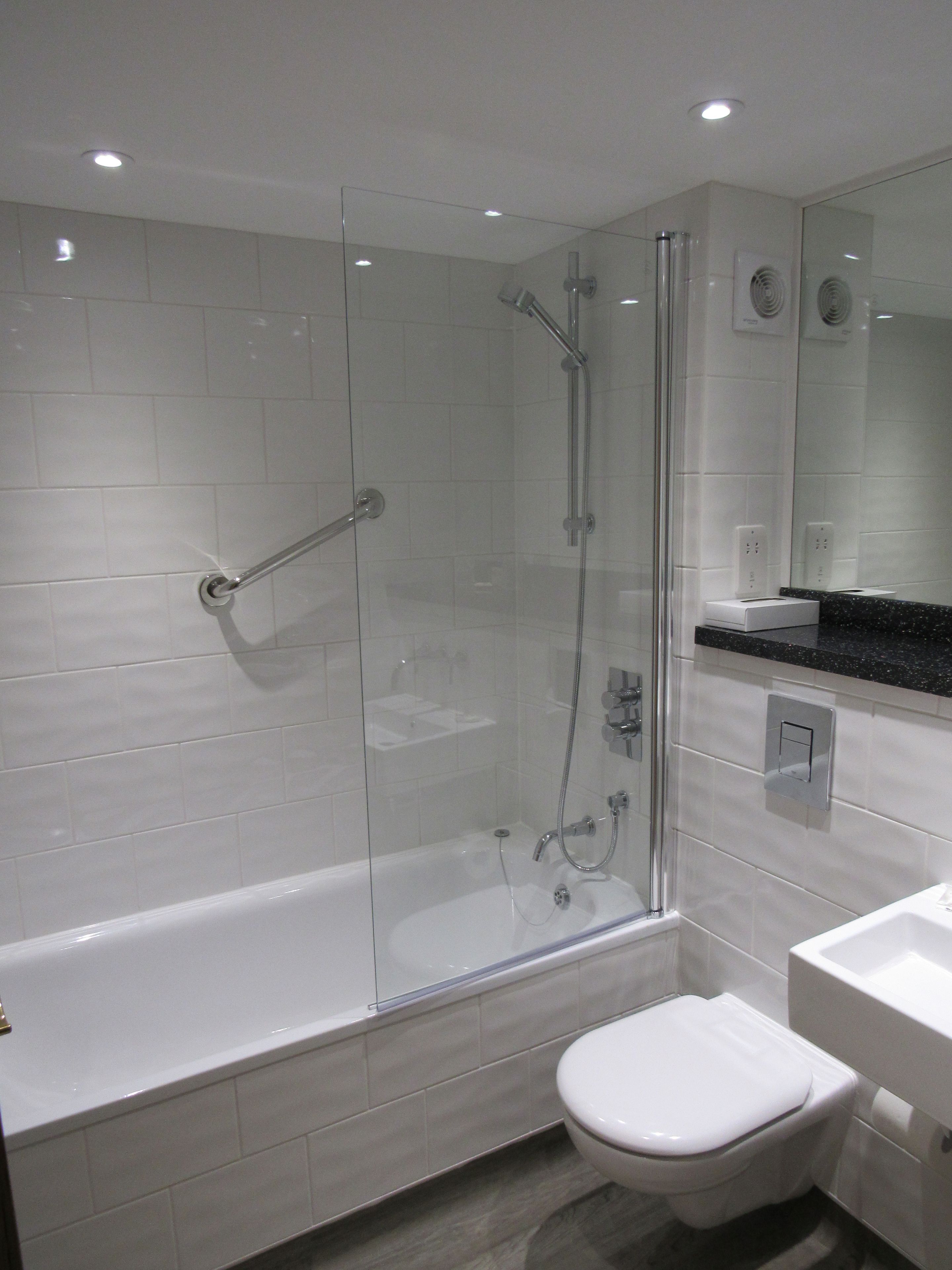 A modern bathroom with a glass-enclosed shower, a white toilet, and a sink.