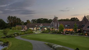 Un campo de golf con un club de campo, un estanque y un cielo despejado.