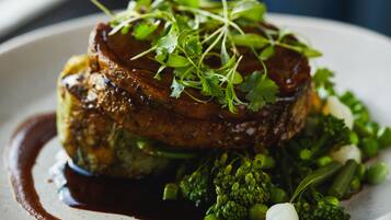Une assiette de nourriture comprenant un steak, des légumes verts et une sauce.