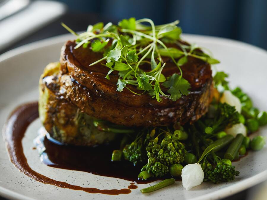Une assiette de nourriture comprenant un steak, des légumes verts et une sauce.