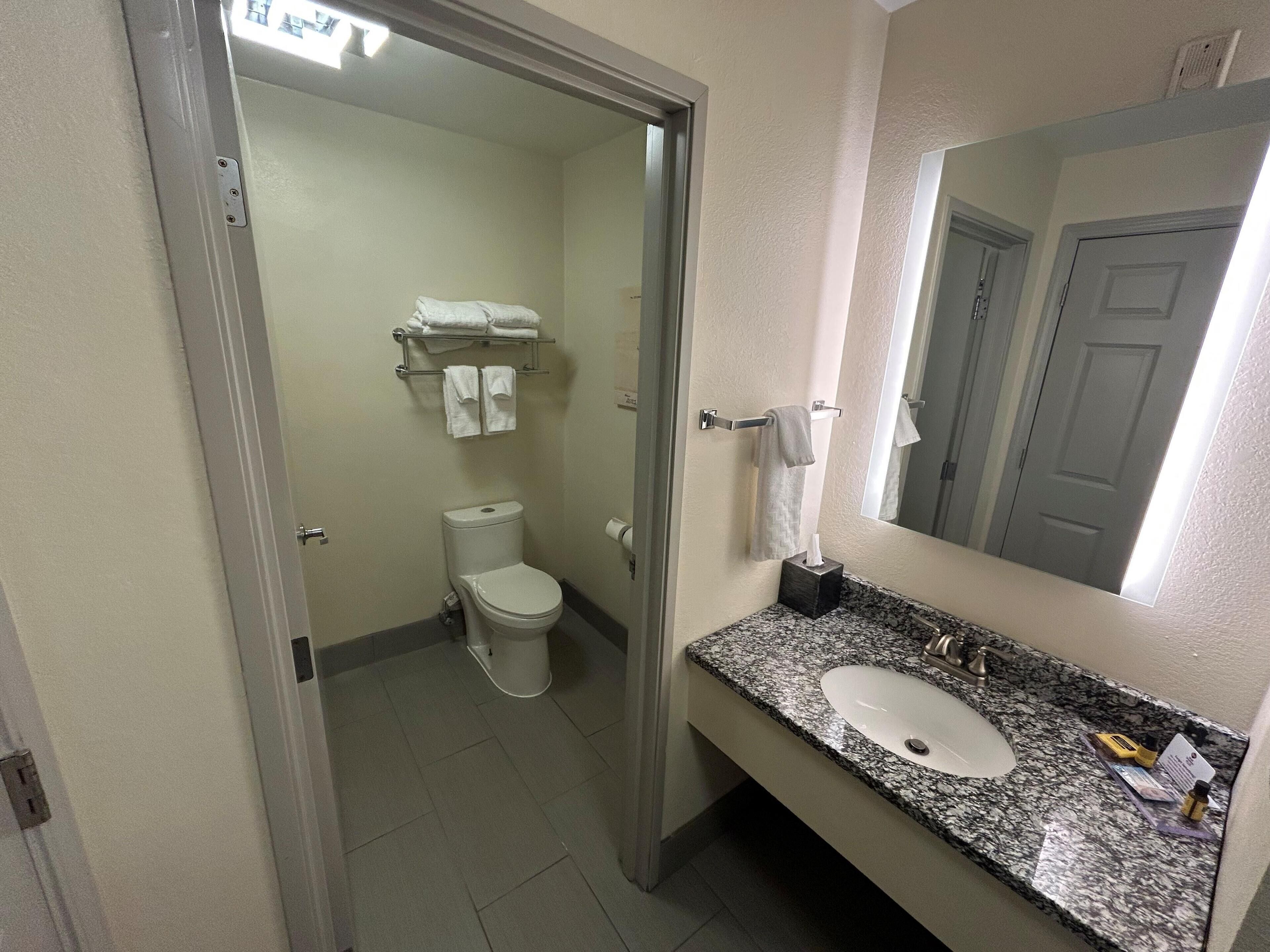 Un baño con inodoro, lavamanos y toallero.