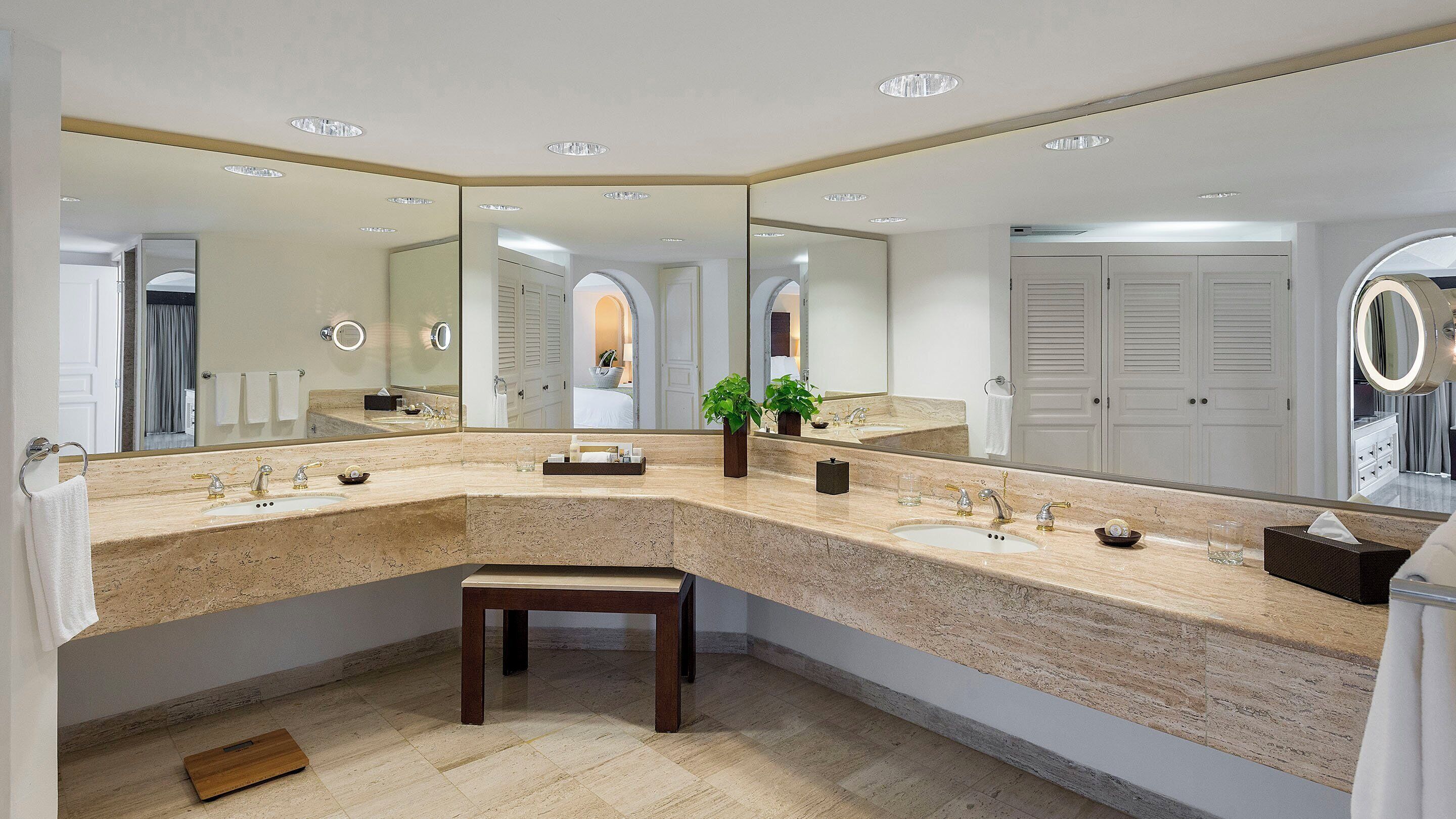 A modern bathroom with a large vanity, multiple sinks, and a large mirror.