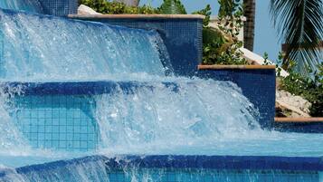 Una piscina con una cascada rodeada de palmeras.