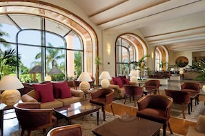 A spacious lobby with high arched windows, comfortable seating, and a well-lit interior.