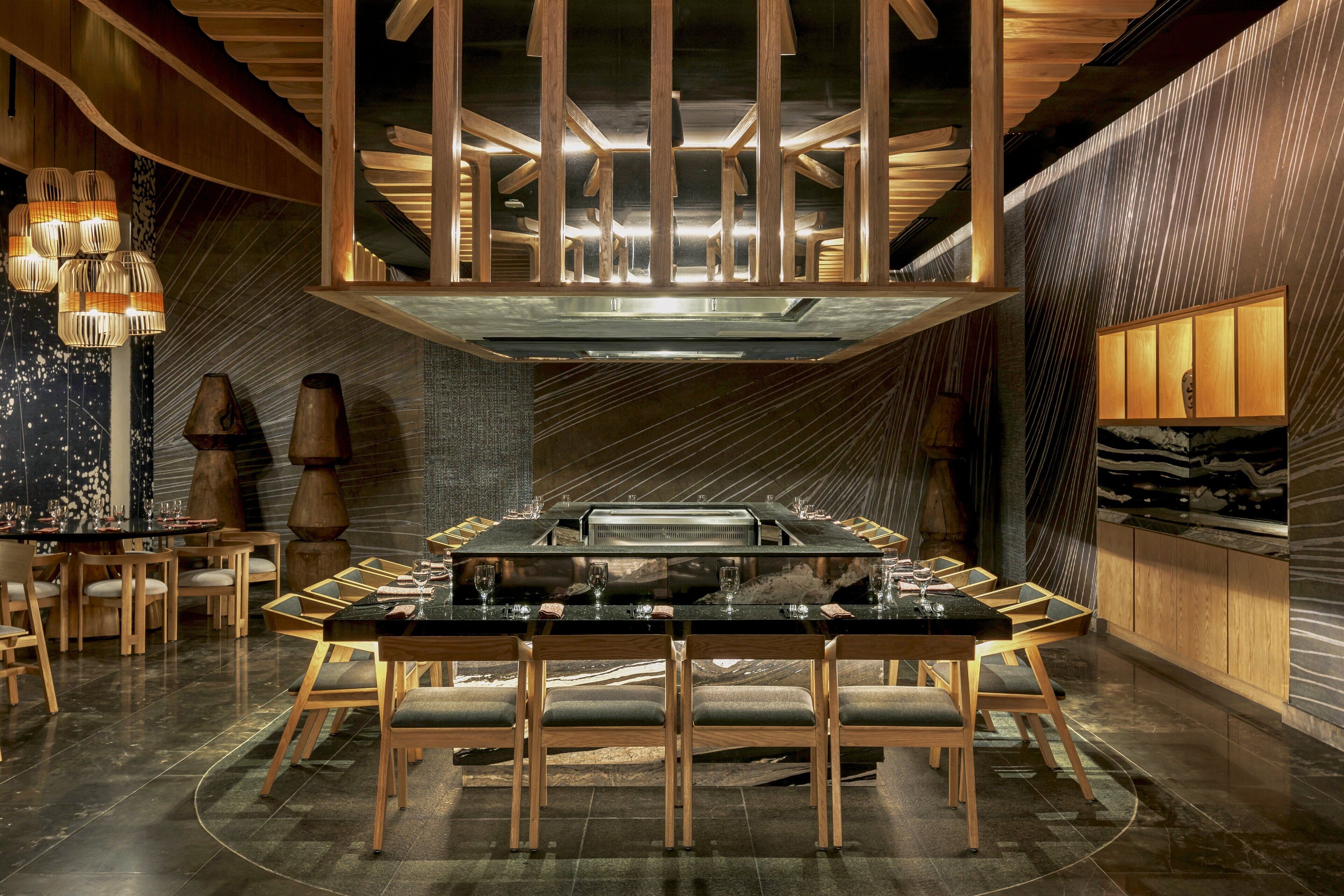 A modern dining area with a central table, wooden chairs, and ambient lighting.