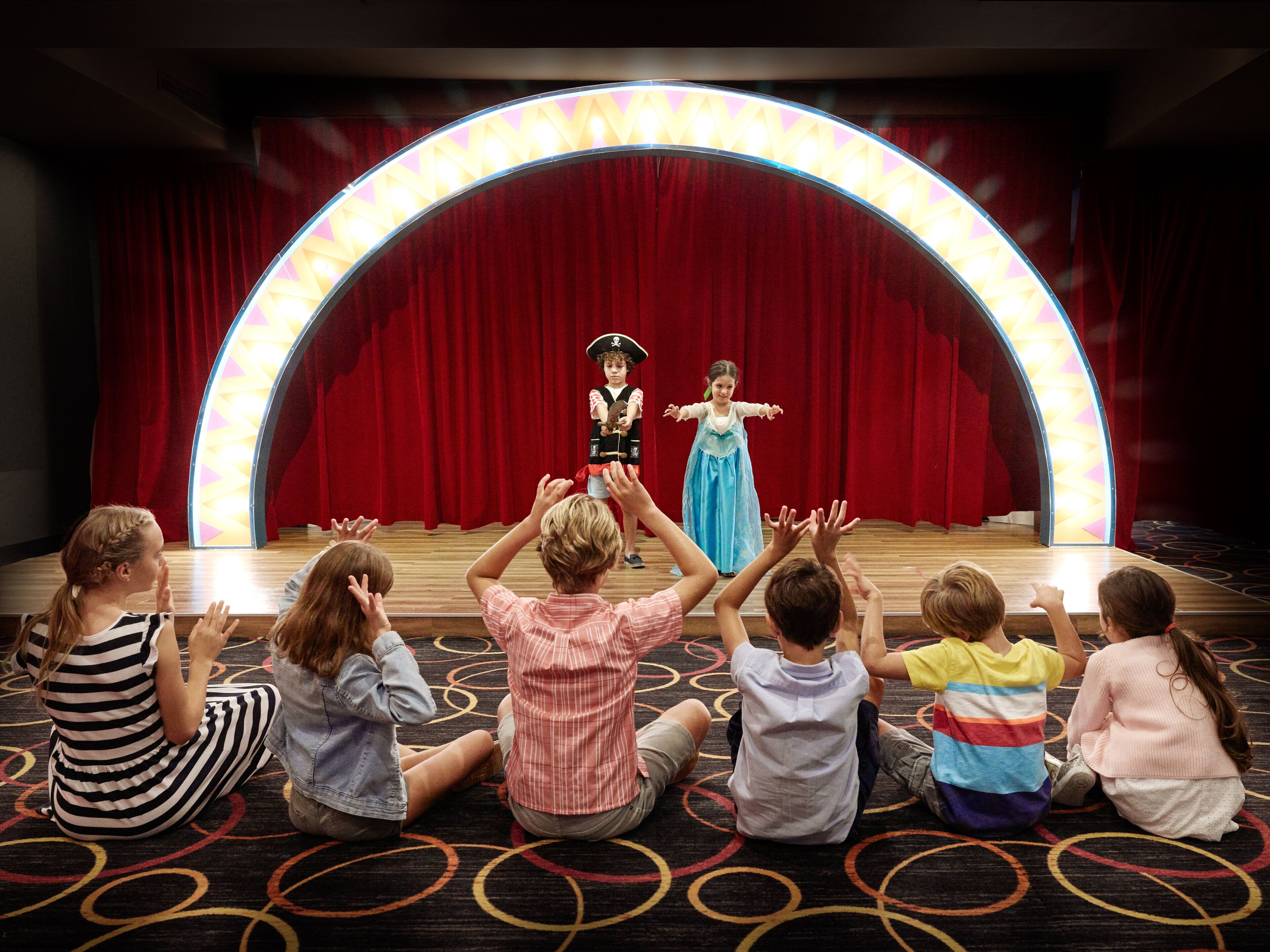 A stage with a red curtain backdrop and a circular light arch.
