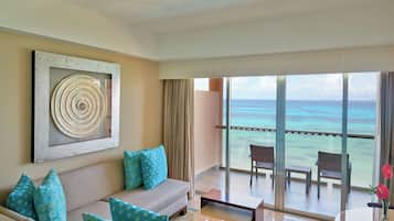 A balcony with a view of the ocean, a sofa with patterned cushions, and a table with a vase of flowers.
