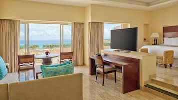 A hotel room with a bed, a desk, a television, and a view of the ocean.