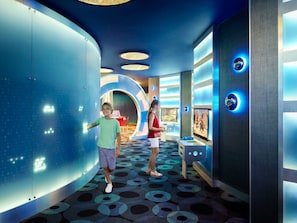 A modern interior with curved walls, a patterned floor, and a digital display.