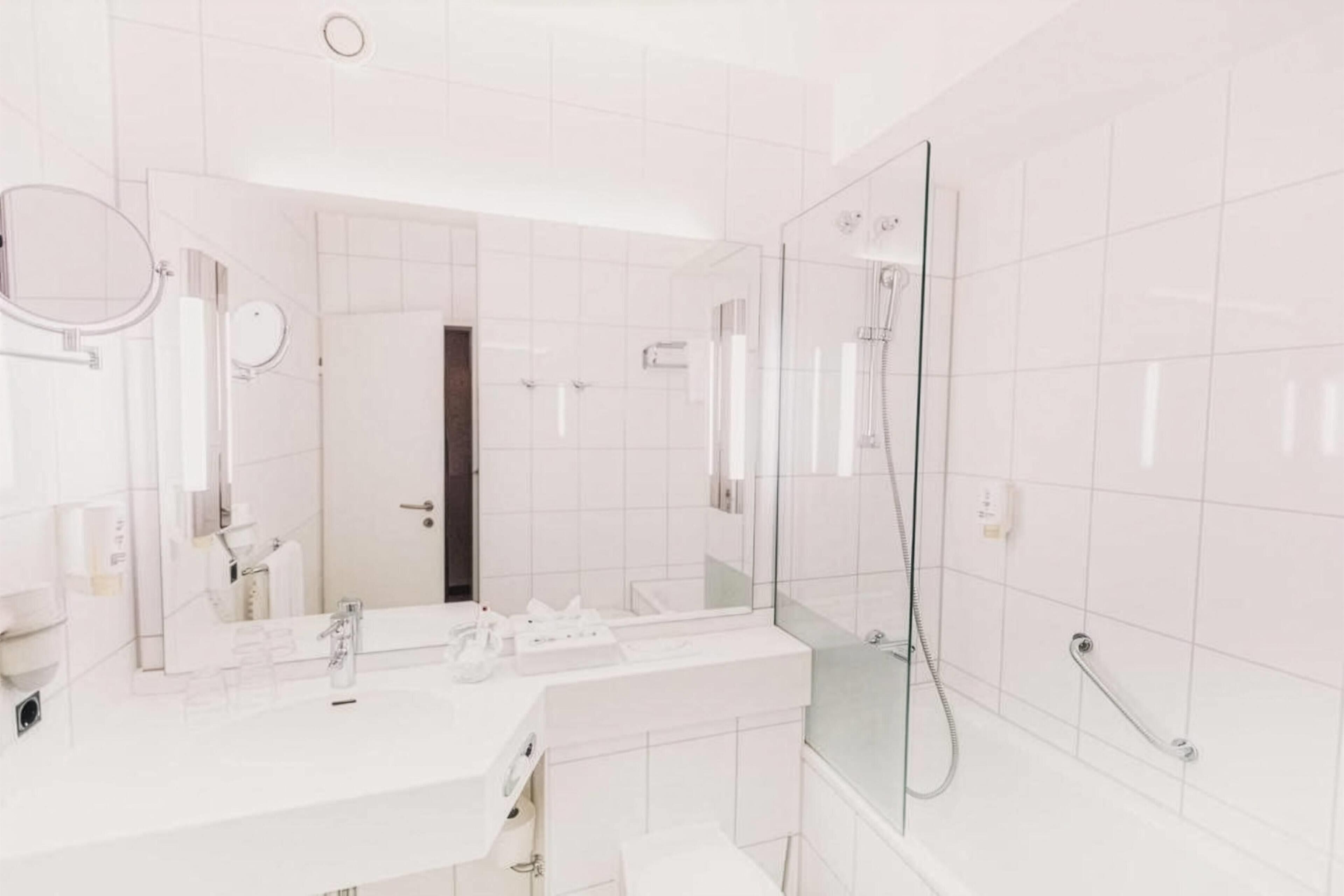 A modern bathroom with a large mirror, a shower, and a toilet.
