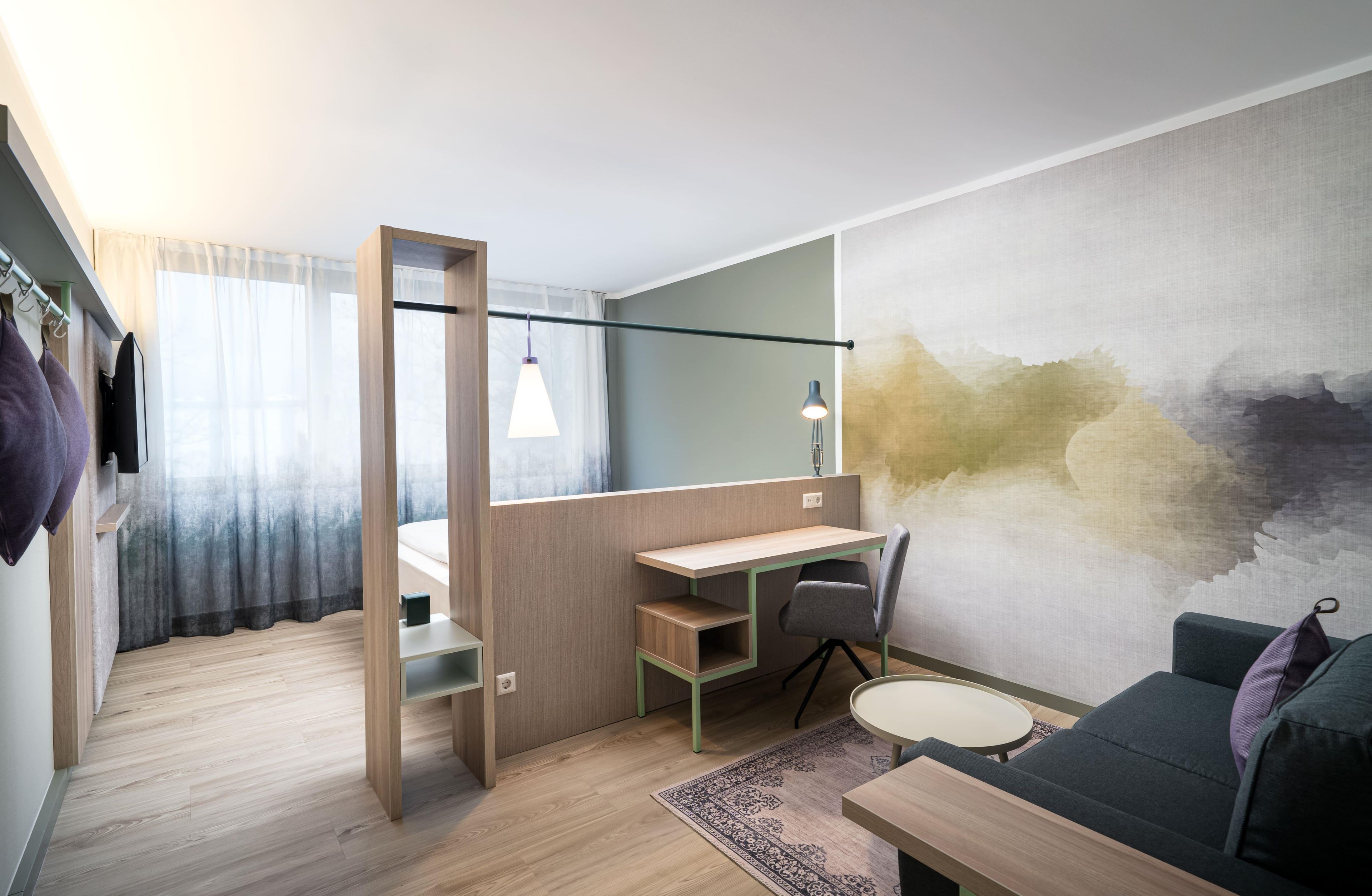 Une chambre moderne et compacte, équipée d’un bureau, d’une chaise et d’une petite table.