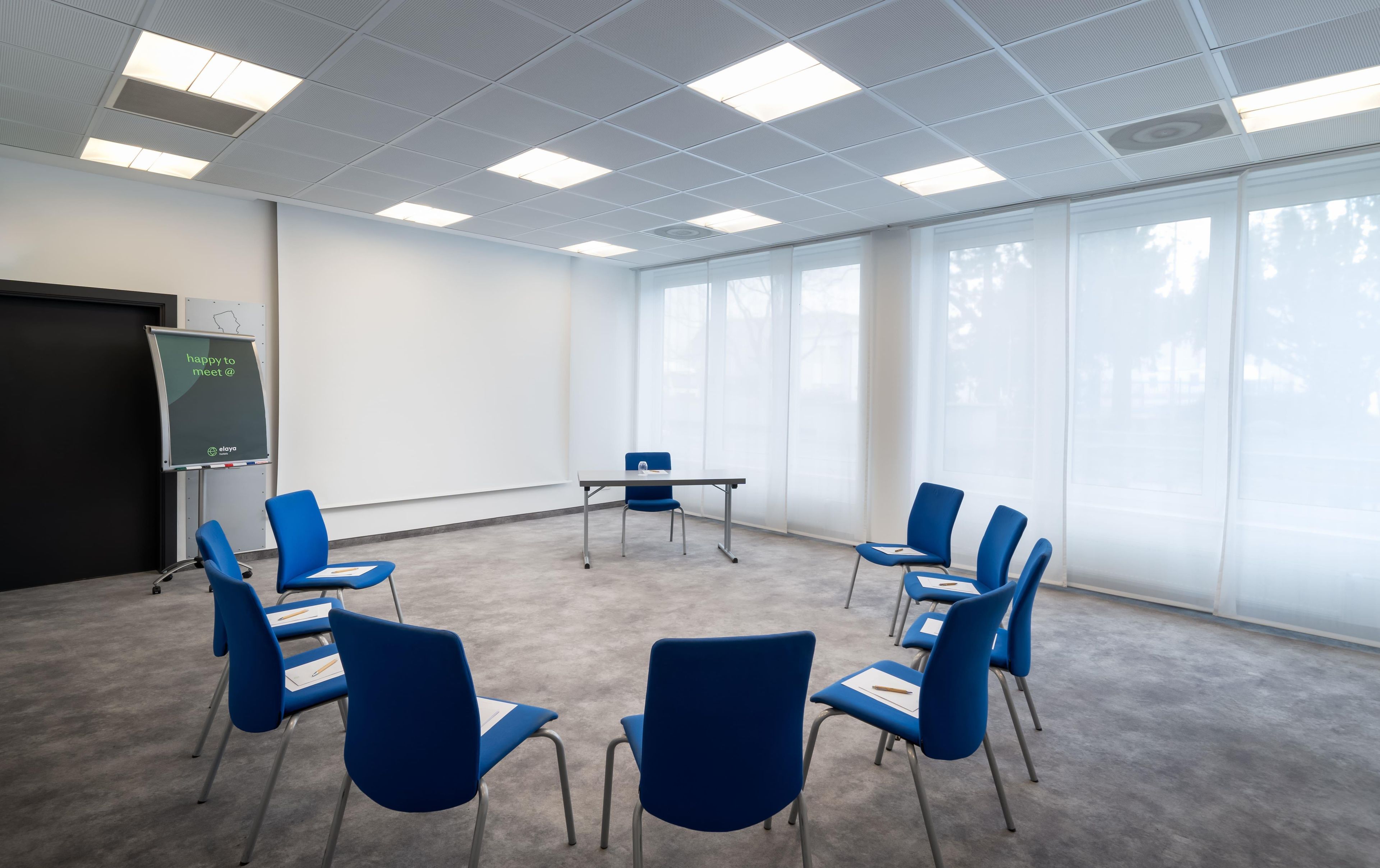 A conference room with a whiteboard, blue chairs, and large windows.